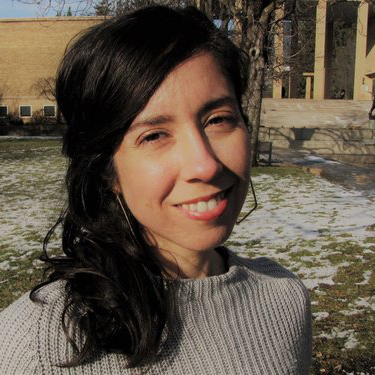 portrait of Carmen, outside in the grass in front of a buliding