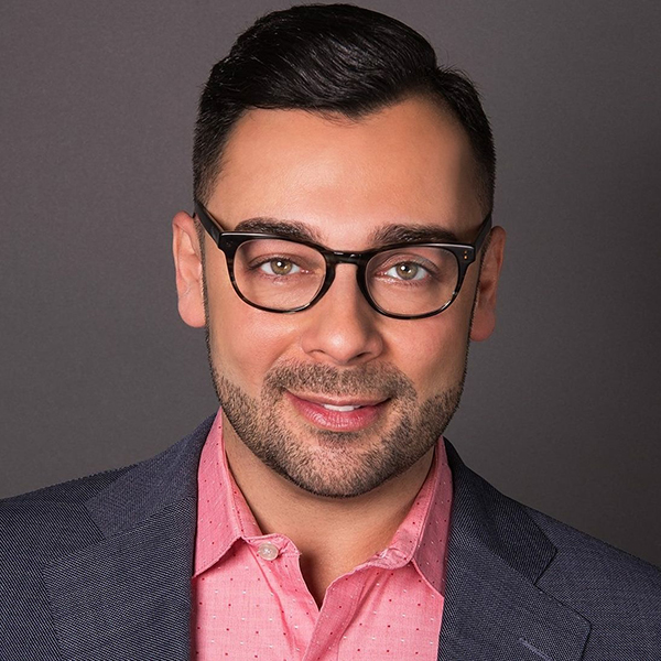 headshot of Edgar Villanueva in a gray suit and pink shirt