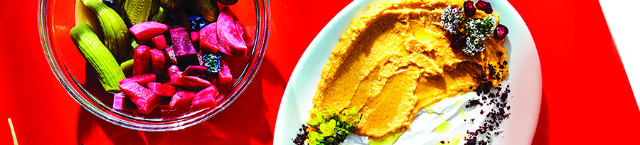 two plates of brightly colored food on a red background
