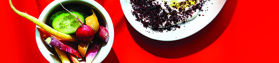 A bowl of brightly colored vegetables on a red background