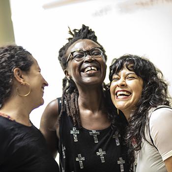 three people stading in a group and laughing